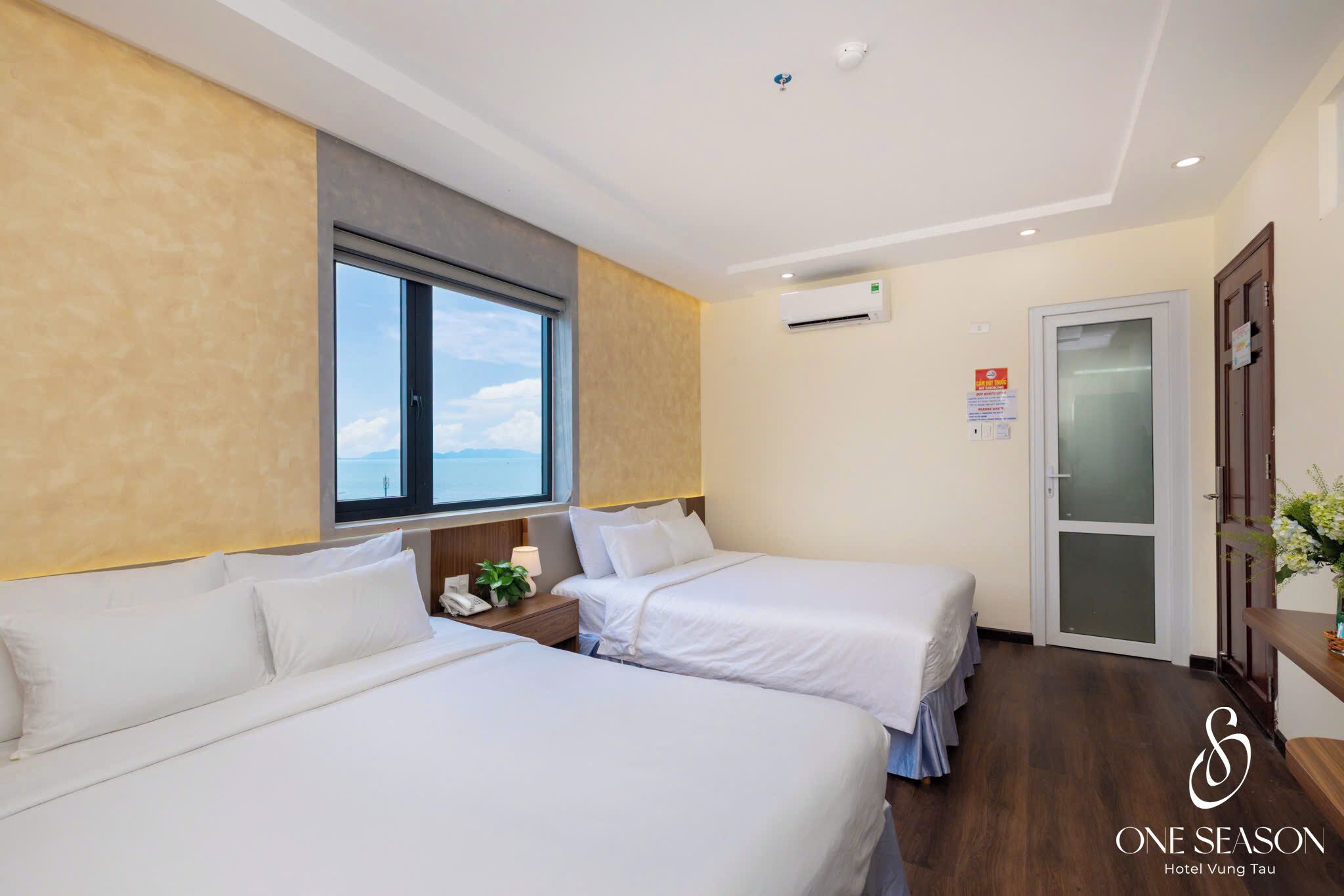 Ein Hotelzimmer mit zwei Betten, einem Fenster, einer Klimaanlage und einer Tür.