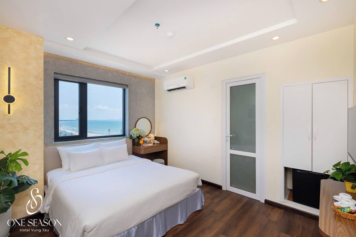Ein Hotelzimmer mit Bett, Fenster mit Aussicht, Schreibtisch mit Spiegel und Kleiderschrank.