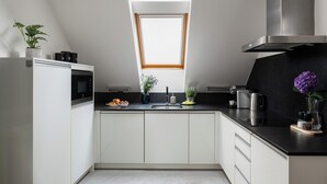 Una cocina moderna con armarios blancos, encimera negra, tragaluz y campana extractora de acero inoxidable.