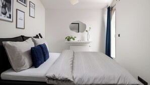 Un dormitorio moderno con una cama, una mesita de noche con espejo y cuadros en la pared.