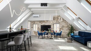 Un espacio habitable moderno tipo loft con comedor, pared de acento de piedra y un televisor grande.