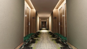 Un couloir d’hôtel aux murs en bois, aux portes numérotées et au sol recouvert de moquette.