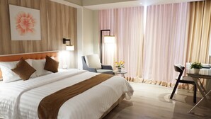 Une chambre d’hôtel avec un grand lit, un bureau, une chaise et une fenêtre avec des rideaux.