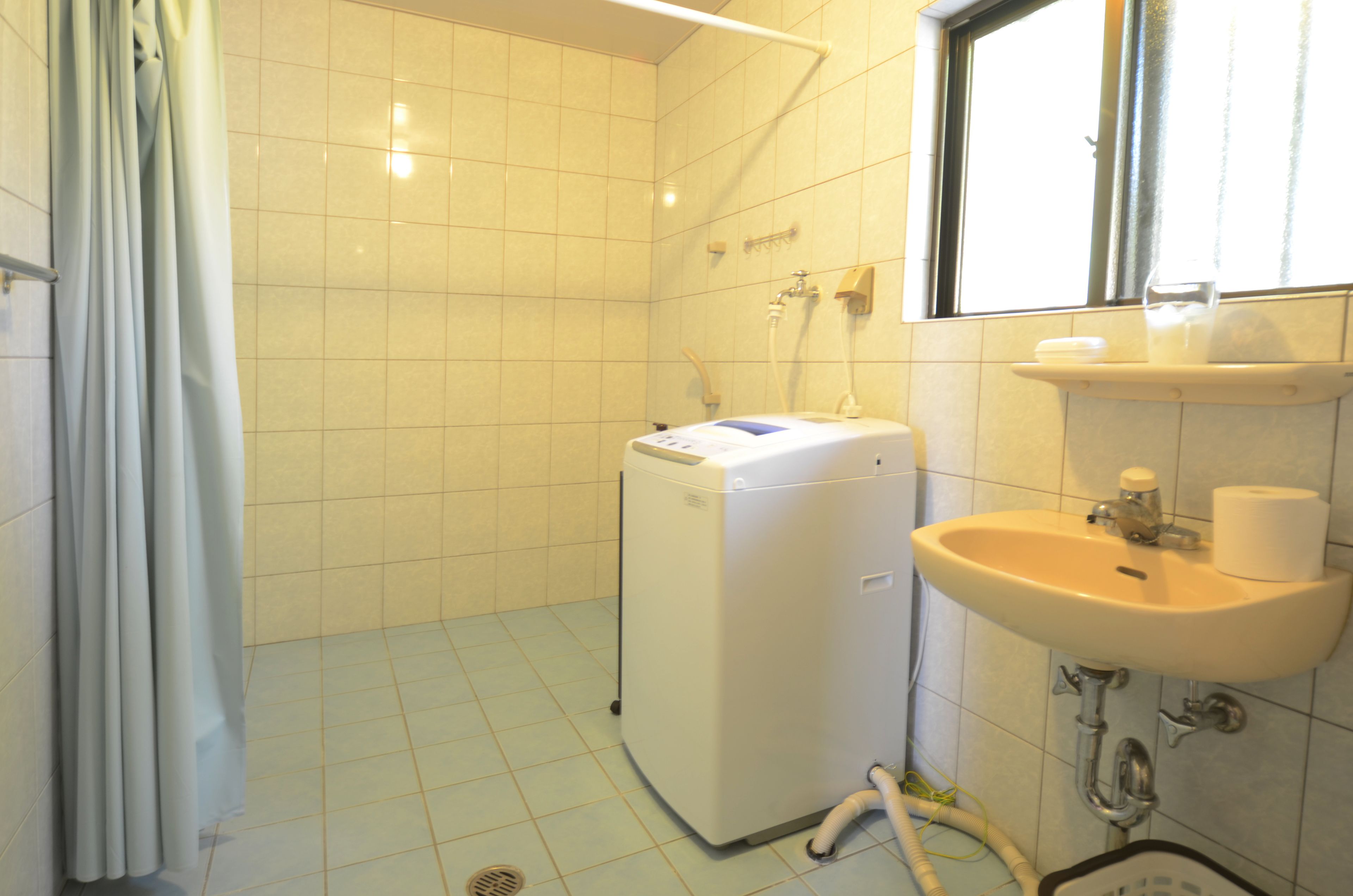 A small bathroom with a washing machine, a sink, and a window.