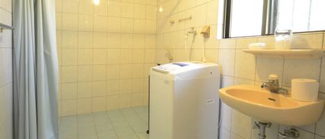 A small bathroom with a washing machine, a sink, and a window.