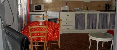Une cuisine équipée d’une table à manger, de chaises, d’un four à micro-ondes, d’une cuisinière et de placards.