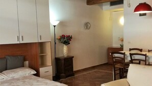 A bedroom with a bed, a nightstand, a dresser, a chair, and a dining table with chairs. - Agriturismo Borgo Stella (Montespertoli)