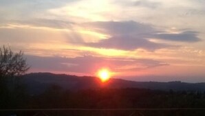 A swimming pool with a view of the sunset over a hilly landscape. - Agriturismo Borgo Stella (Montespertoli)