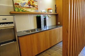 A kitchen with wooden cabinets, a stainless steel refrigerator, and a sink.