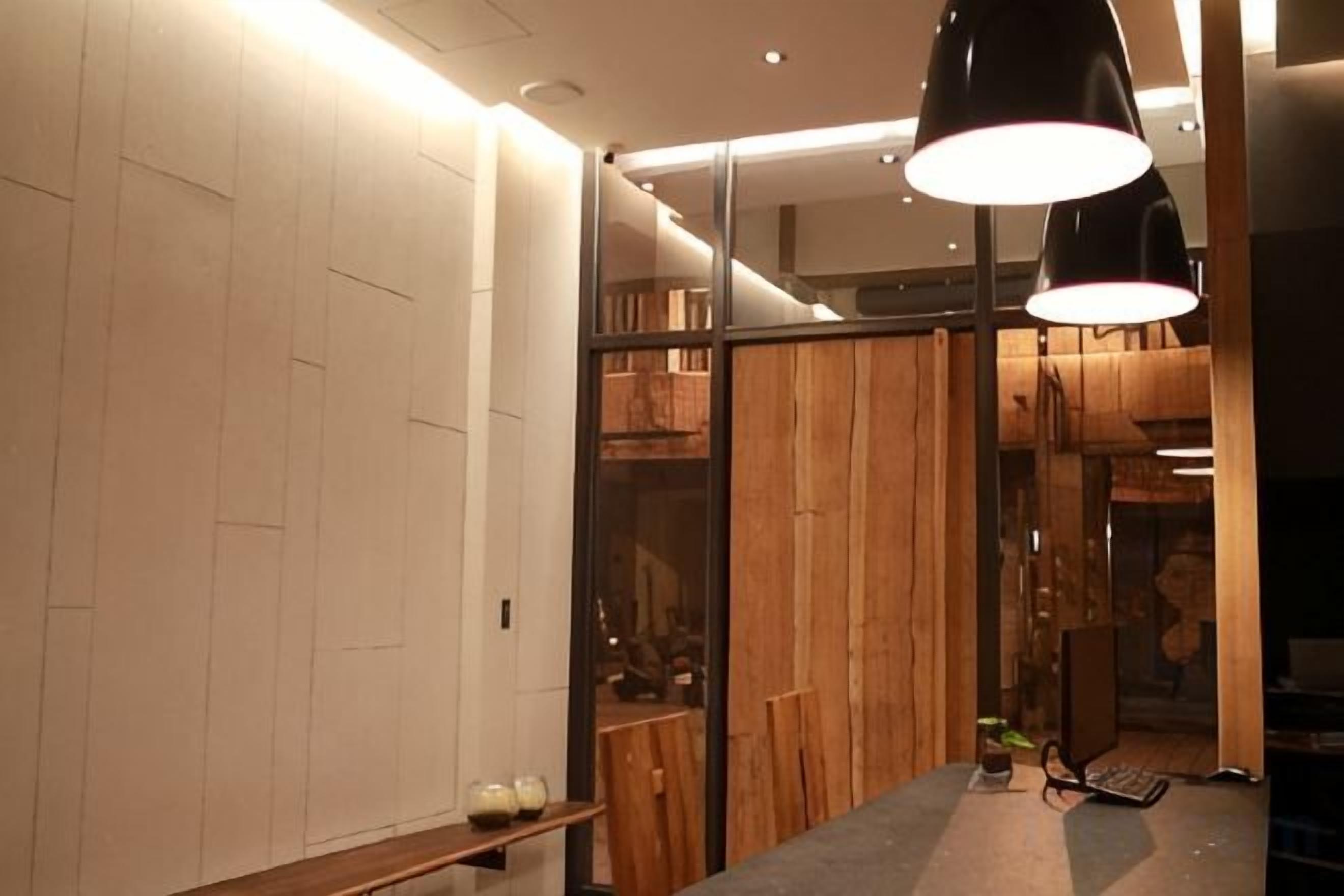 A modern interior with a wooden partition, a desk with a lamp, and a shelf with items.