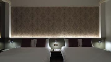 Ein Hotelzimmer mit zwei Betten, einem gemusterten Kopfteil, Nachttischlampen und einem Nachttisch mit Lampe.