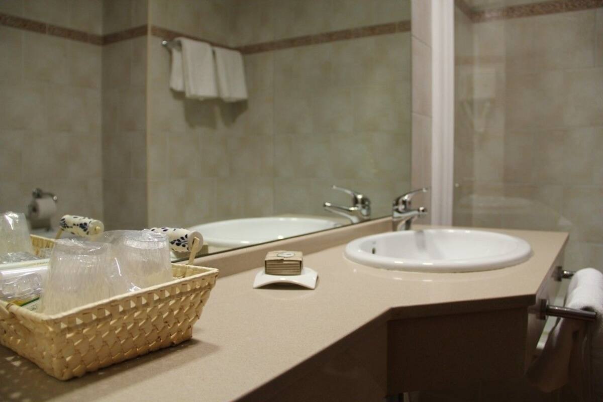 A bathroom with two sinks, a mirror, a towel rack, and a basket with toiletries.