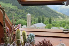 Vista desde una ventana de un paisaje montañoso con un edificio a lo lejos.