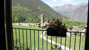 A balcony with a view of a mountain landscape, a church tower, and a flower box. - Hotel El Rantiner (La Vall de Boi)