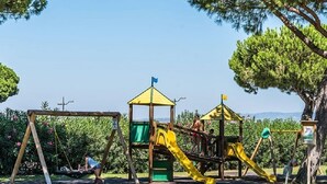 Un parque infantil con un tobogán amarillo y un pequeño refugio.