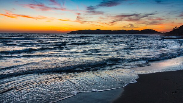 Una playa con olas al atardecer.