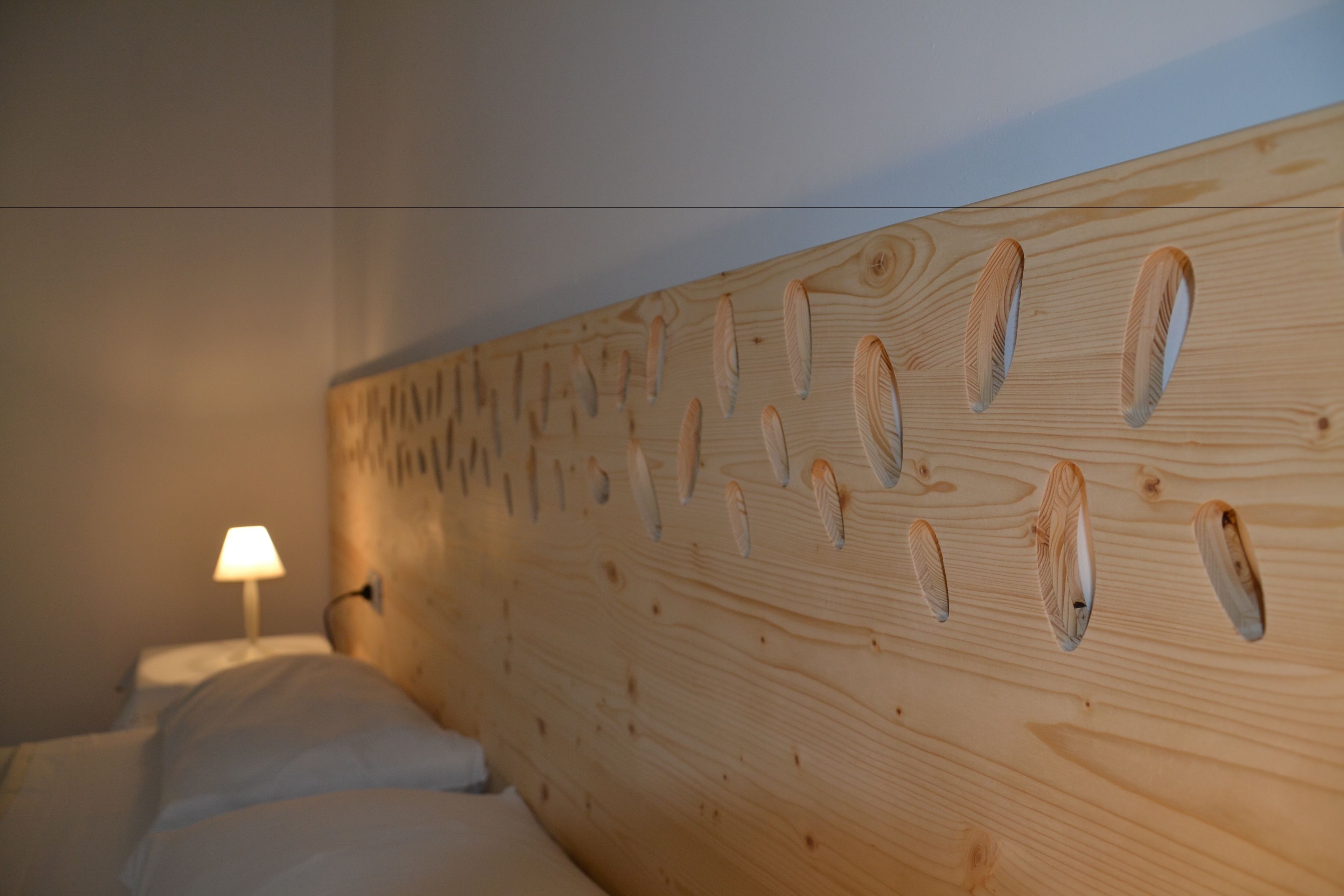 A wooden headboard with a unique pattern of oval shapes.