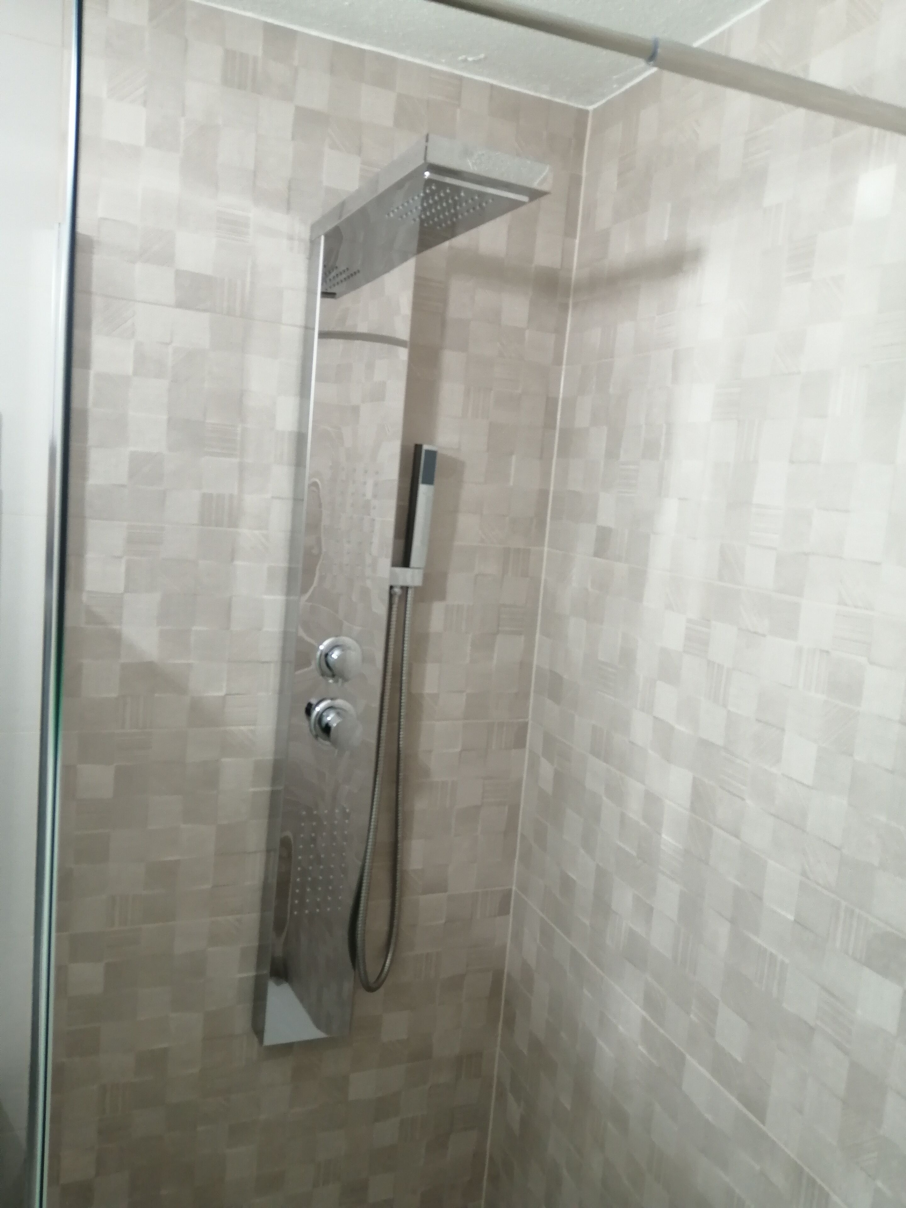 A shower with a handheld showerhead and a wall-mounted rain showerhead.