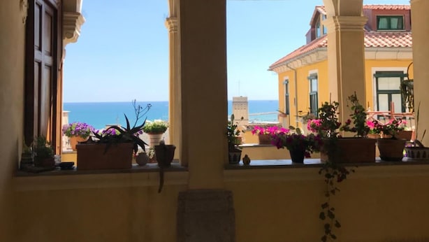 Uma área externa coberta, com arcos e plantas em vasos.