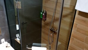 A modern bathroom with a glass-enclosed shower, a white toilet, and a sink with a mirror. - Qlio Hotel (Kota Kinabalu)