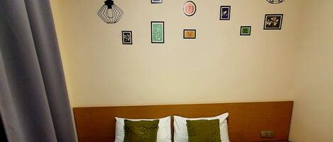 Una habitación de hotel con una cama bien hecha, un cabecero de madera y una mesita de noche con una lámpara.