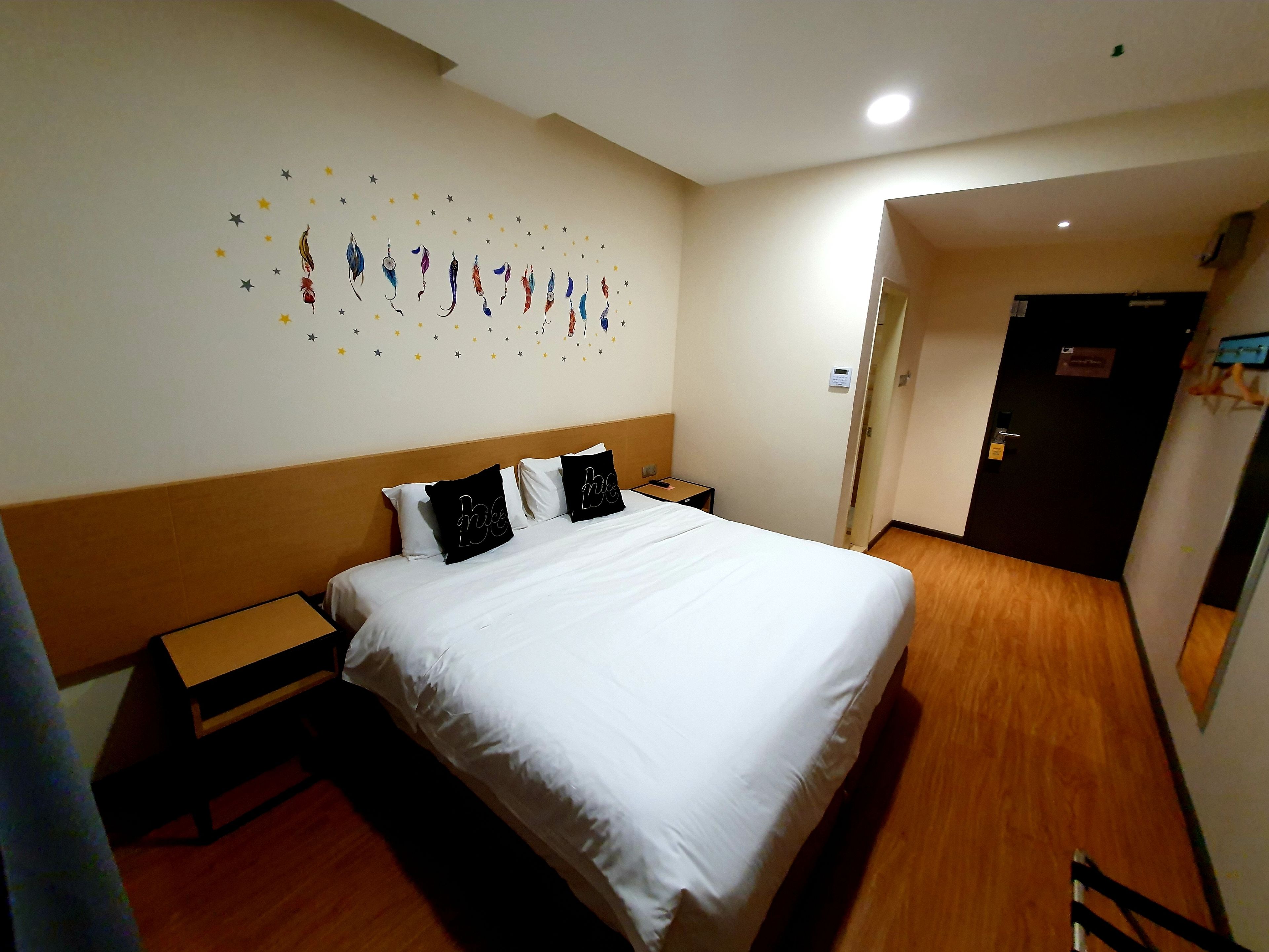 Habitación de hotel con una cama, una mesita de noche, una pequeña mesa y una pared decorada con estrellas.