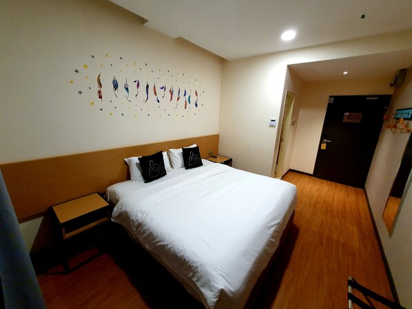 Habitación de hotel con una cama, una mesita de noche, una pequeña mesa y una pared decorada con estrellas.