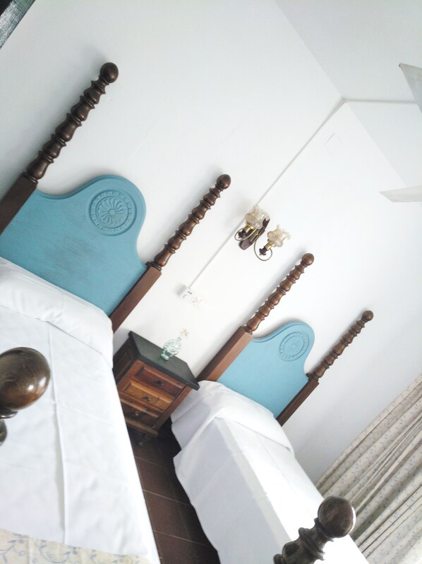 A bedroom with two beds, a nightstand, and a wall-mounted light fixture. - Zhimbad B&B by the sea (Capdepera)