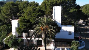 Un edificio bianco con una torre centrale, circondato da alberi e un piccolo giardino.
