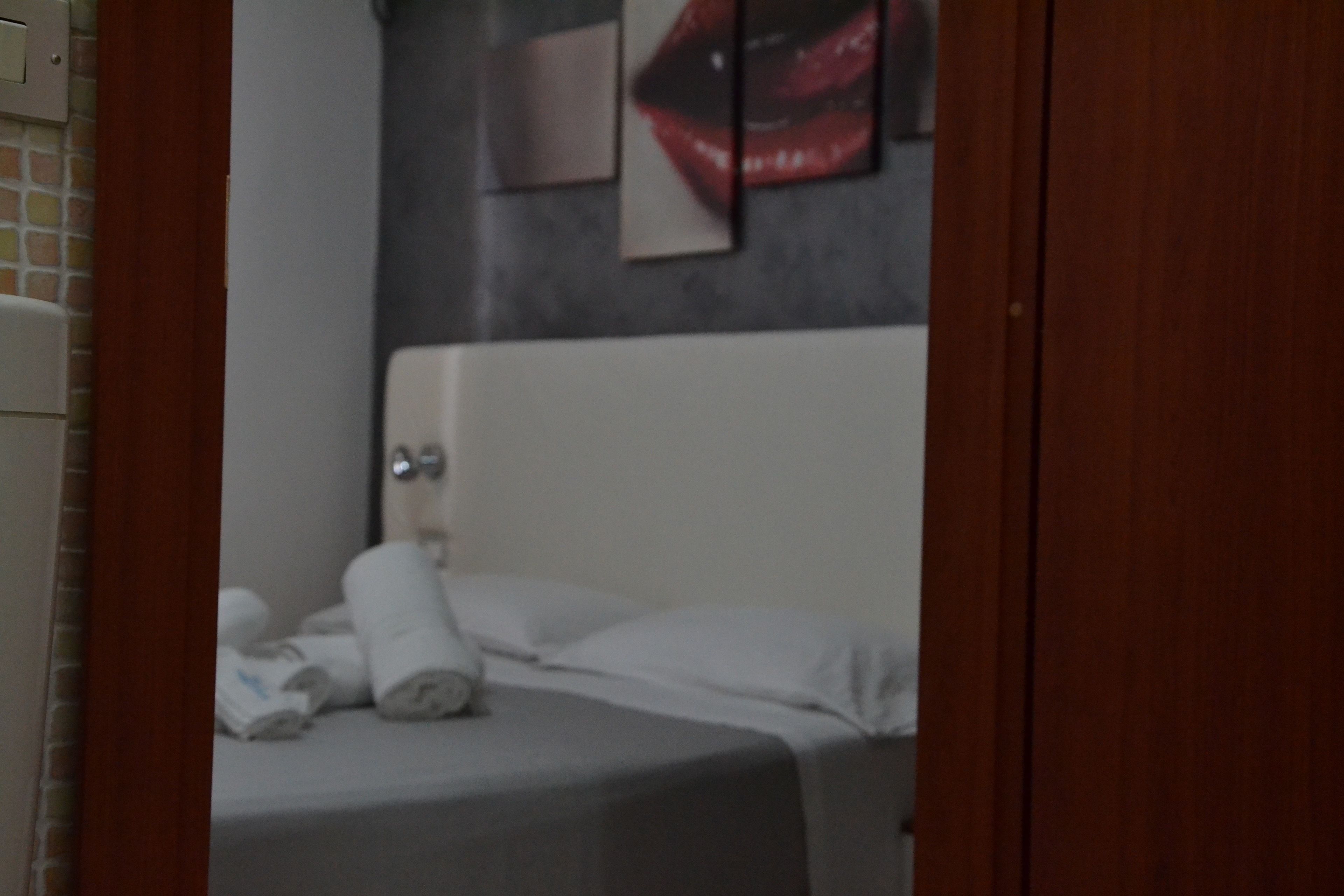 Ein Hotelzimmer mit einem Bett, Kissen und einer Wand mit einem Teil eines Kunstwerks.