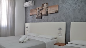 Habitación de hotel con dos camas, una pared gris con textura y un cuadro de un puente.