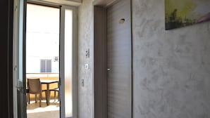 Un pasillo interior con una puerta corredera que da a un espacio exterior con una mesa y sillas.