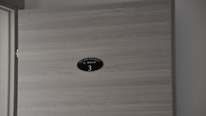 Una habitación con un panel de madera en la pared y un letrero negro que indica el número 3.