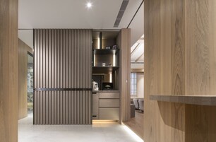 Un vestidor moderno y bien iluminado, con paneles de madera, estantes empotrados y cajones.