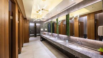 Un baño moderno con tres lavamanos, paneles de madera y un espejo grande.