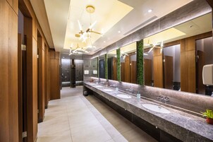 Un baño moderno con tres lavamanos, paneles de madera y un espejo grande.