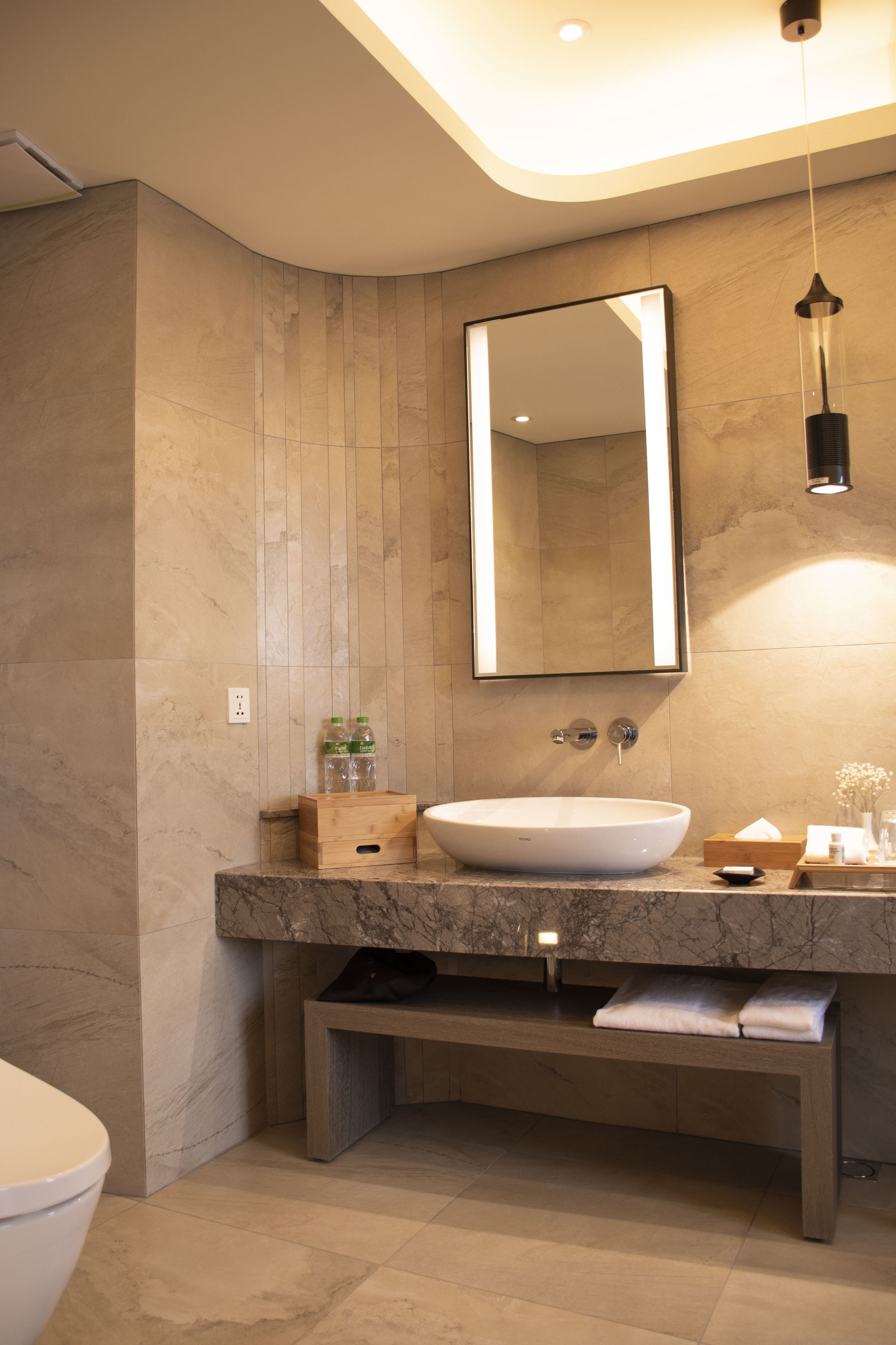 A modern bathroom with a large mirror, a vessel sink, and a bench.