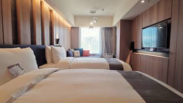 A hotel room with two beds, a flat-screen TV, and a large window with curtains.