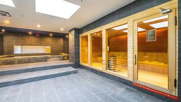 A modern hotel lobby with a reception desk, a staircase, and large wooden-framed windows.
