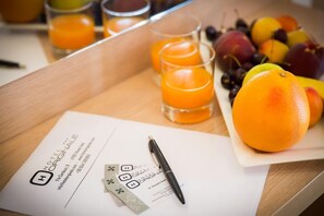 A hotel brochure, a pen, a tray with fruit, and glasses of orange juice. - Hotel Originale (Rimini)