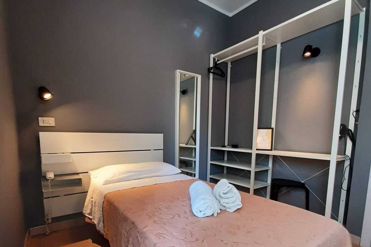 A bedroom with a bed, a wardrobe, and a mirror.
