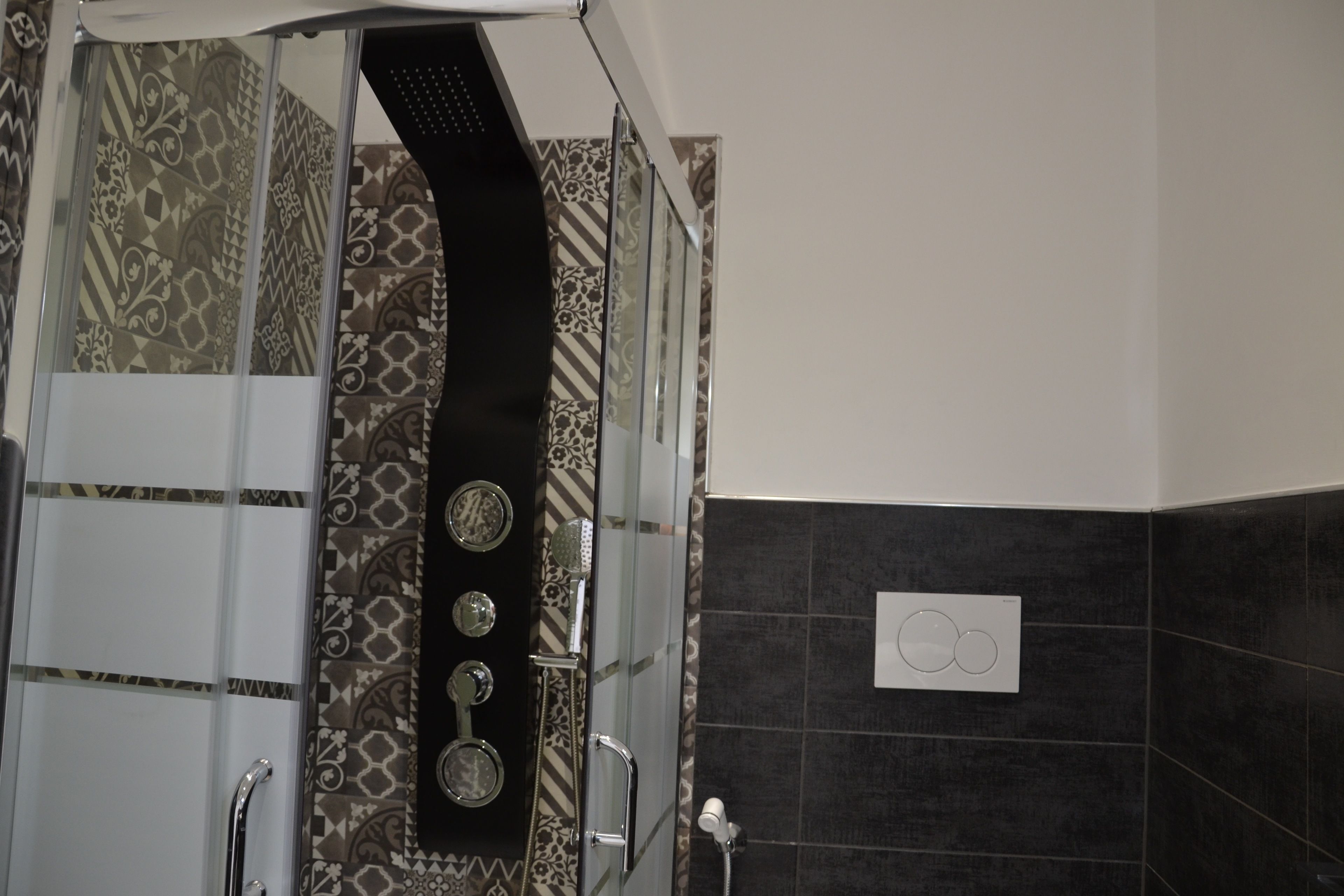 A shower with patterned tiles and a black showerhead.