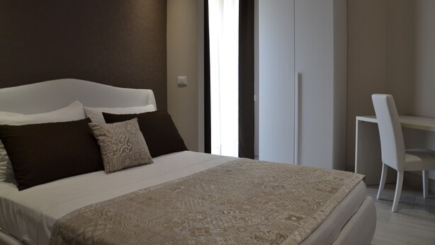 Un dormitorio con cama, una silla y un armario.
