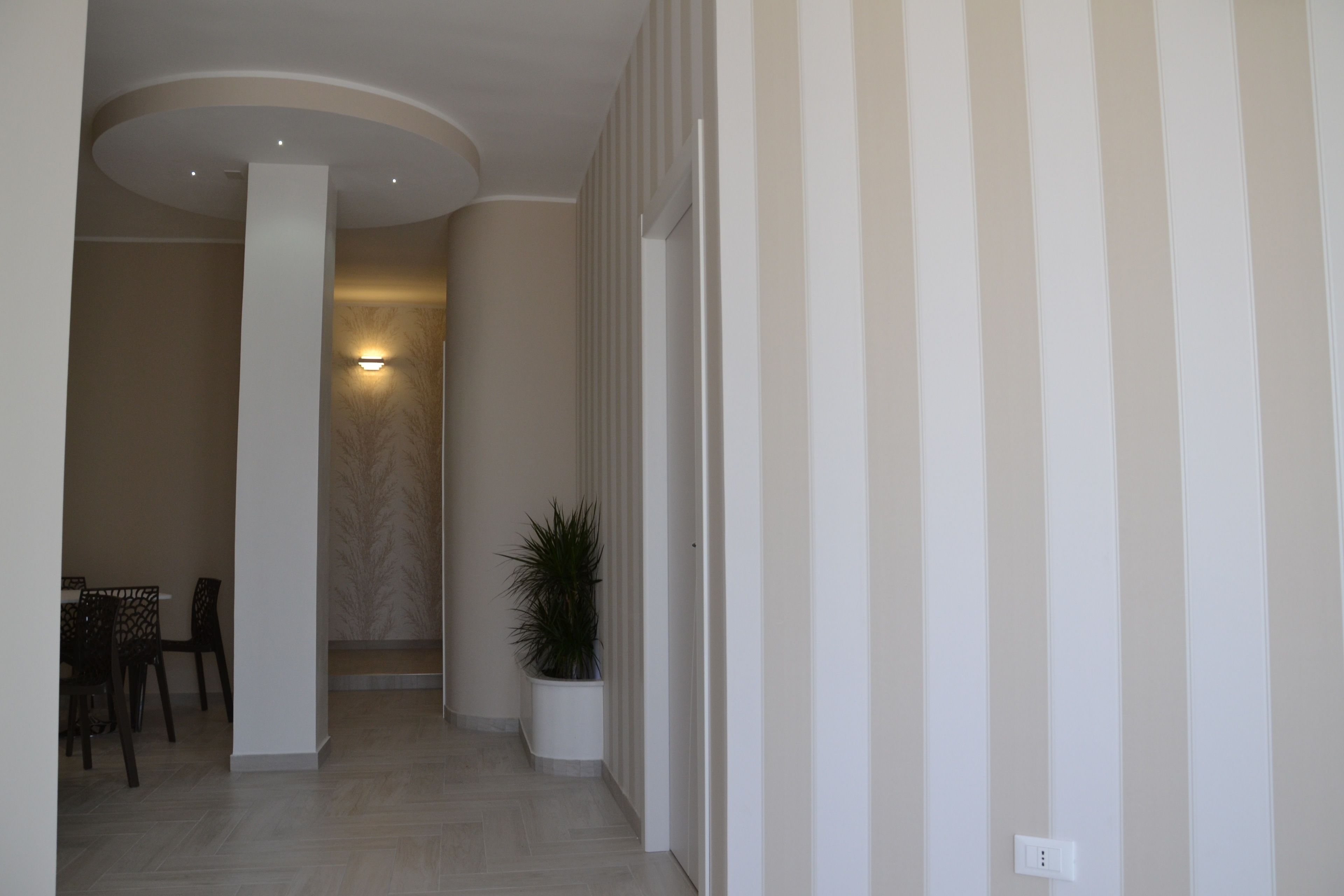 A hallway with a dining area, a potted plant, and a light fixture.