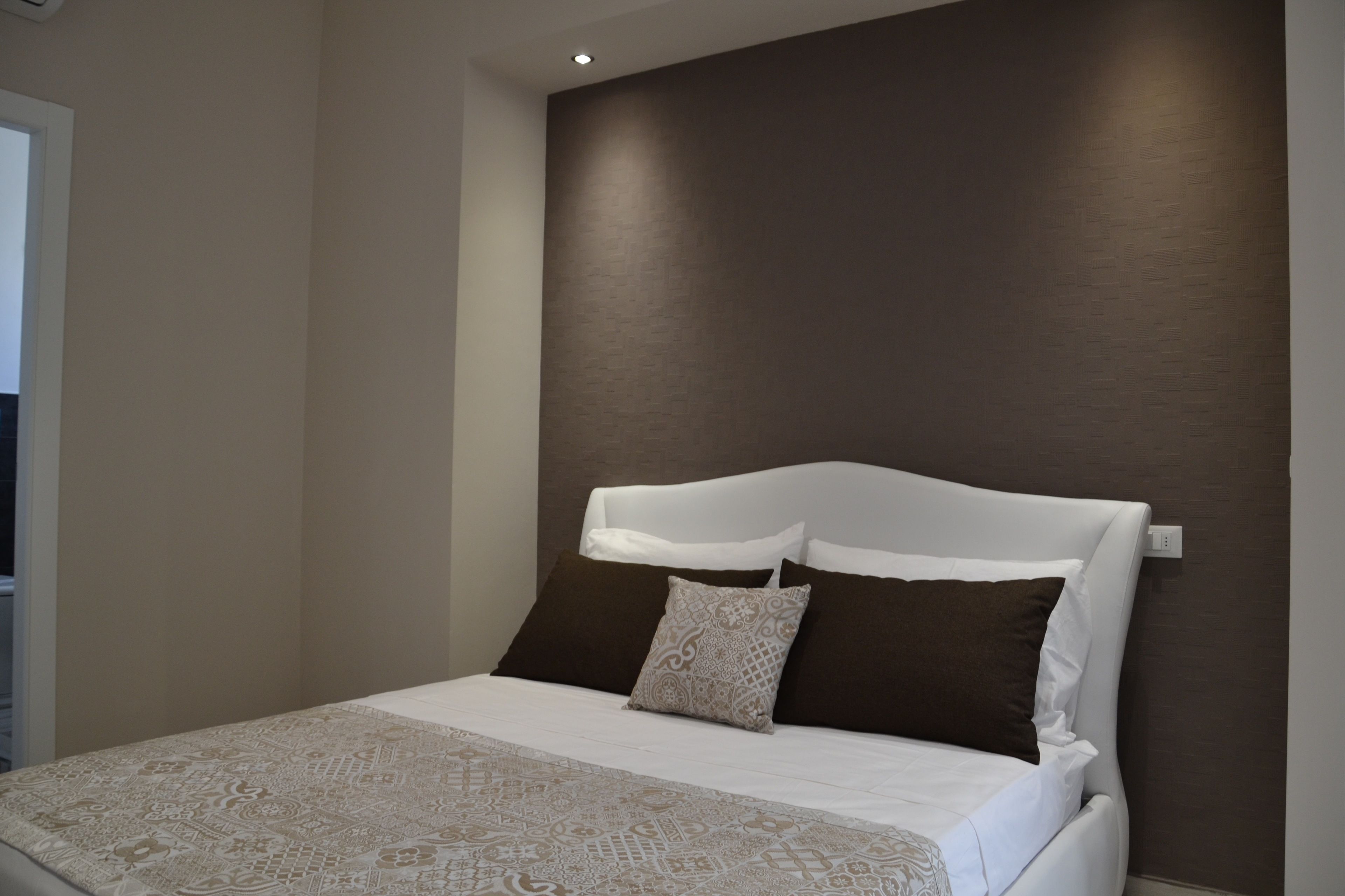 A modern bedroom with a large bed, a headboard, and a patterned bedspread.