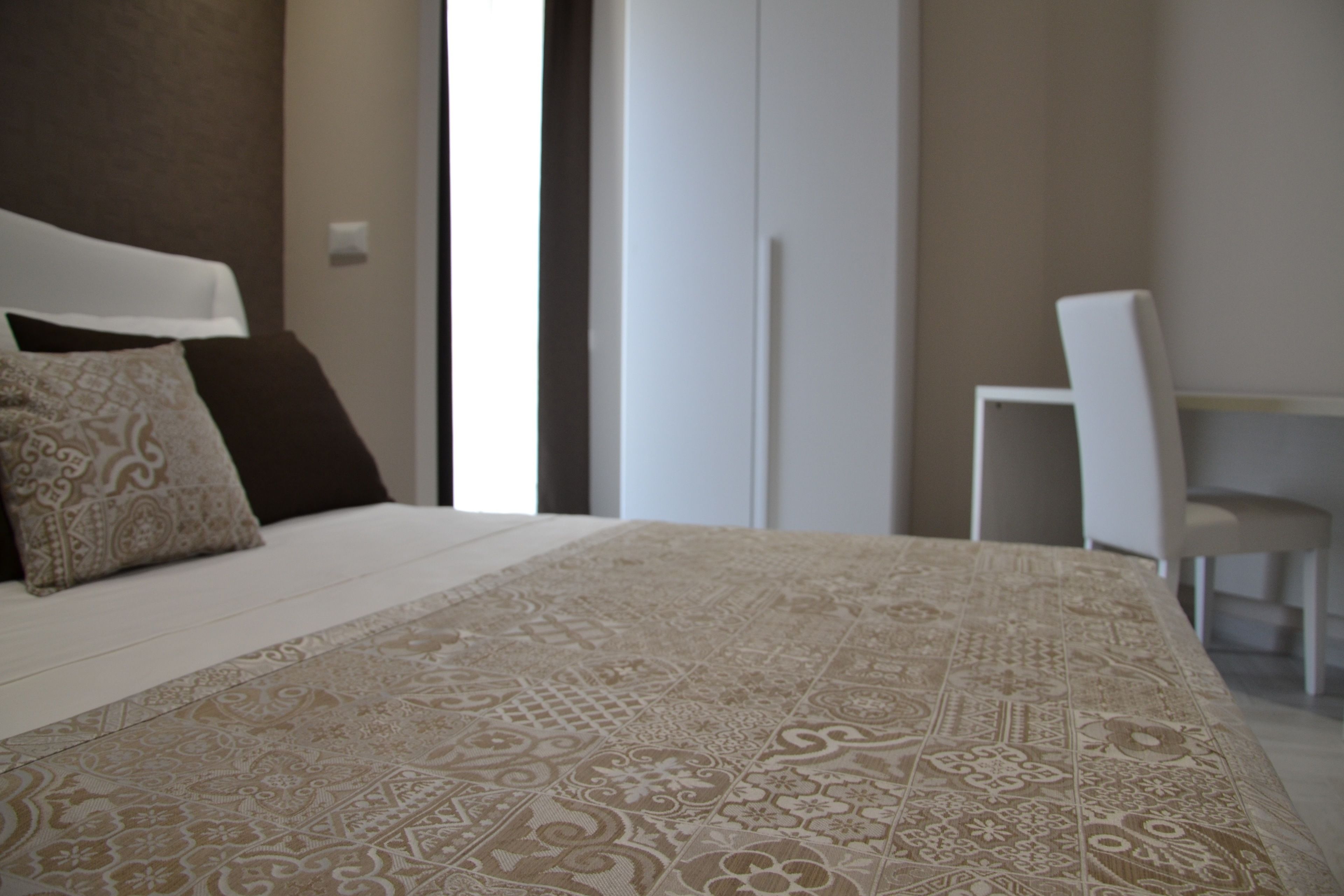 A bedroom with a large bed, a chair, and a wardrobe.