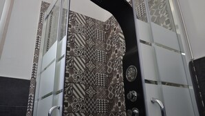 Ducha con cabezal de ducha negro curvado y pared de azulejos estampados.