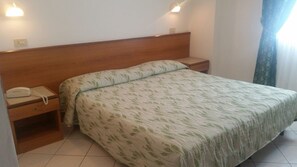 Een slaapkamer met een bed, nachtkastje en telefoon.