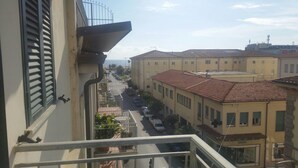 A view from a balcony overlooking a street with buildings, a clear sky, and a distant view of the sea. - Hotel Astoria (Viareggio)