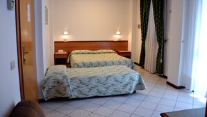 A hotel room with two beds, a wooden headboard, bedside lamps, a telephone, and a door. - Hotel Astoria (Viareggio)